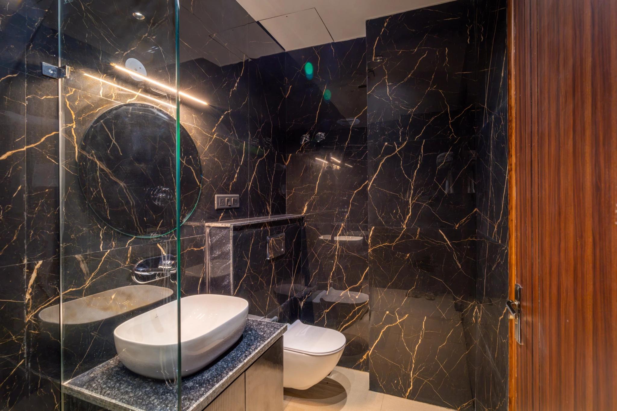 Marble washroom with a vessel basin and glass shower