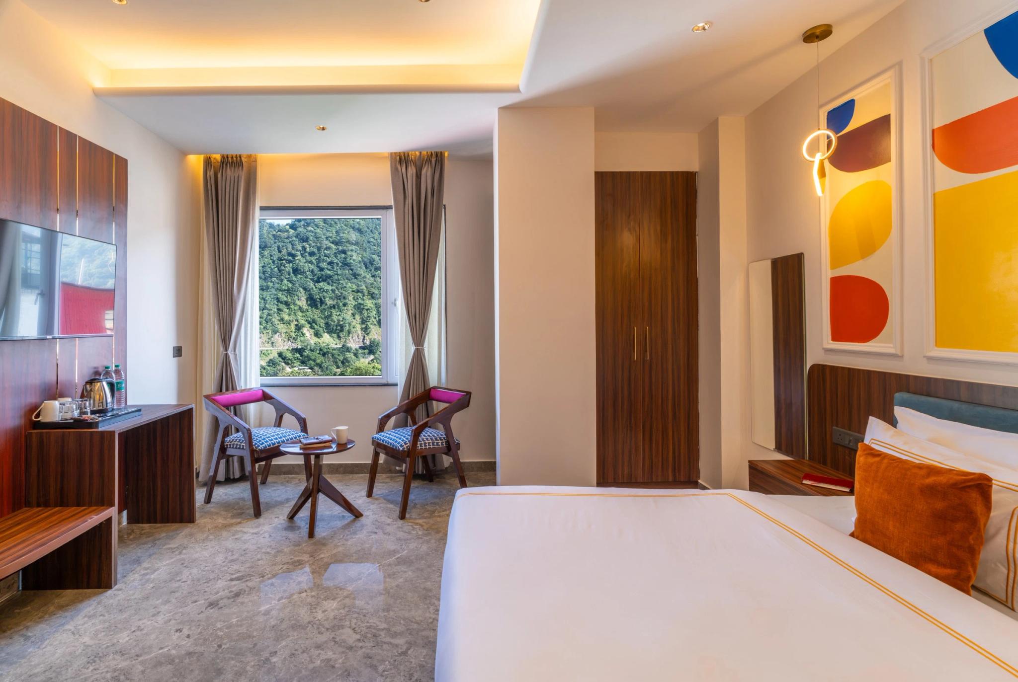 Private room with a double bed, a sitting nook and a window onto the hills