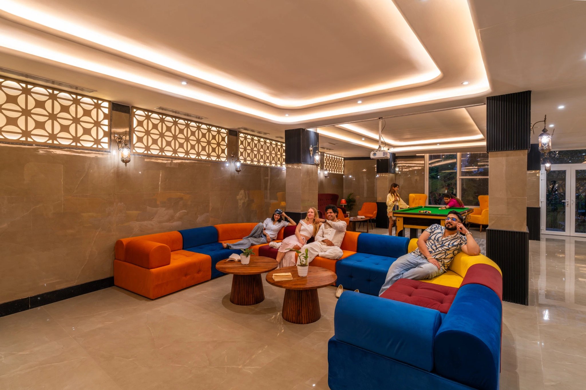 Guests unwinding on bright velvet sofas in the FRAZ lounge